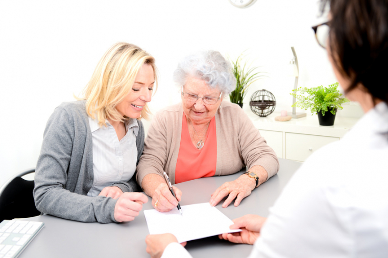 elderly senior woman with daughter signature legacy heritage testament document in lawyer notary office